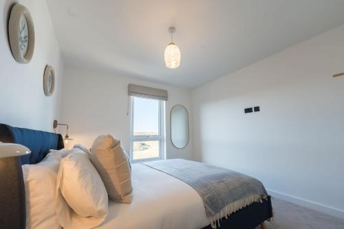 a bedroom with a bed with pillows and a window at Gwel Y Mor Penthouse By Birch Stays New Home in Amlwch