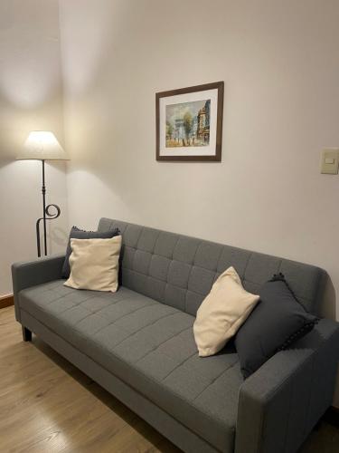 a gray couch with two pillows sitting in a living room at Apartamento Completo en el centro de Durazno in Durazno