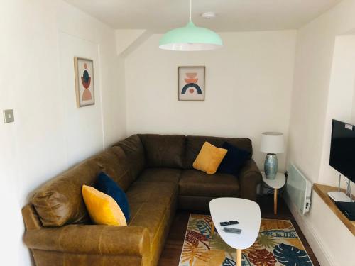 a living room with a brown couch and a table at Mount Cottage in Newcastle Emlyn