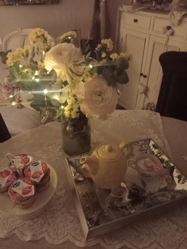 a table with a tea pot and a vase of flowers at B&B Luna in Castelvetro di Modena