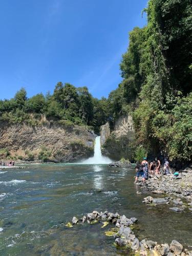 a group of people swimming in a river with a waterfall at Casa entré Fundos in Lago Ranco