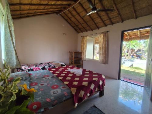 a bedroom with two beds and a large window at Little Banana Homestay in Hampi