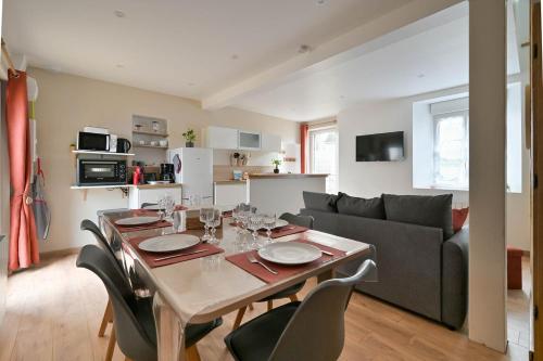 un salon avec une table avec des chaises et un canapé dans l'établissement Gîte entre terre et mer, à Mannevillette