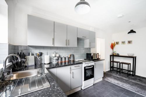 a kitchen with white cabinets and a sink at Cosy 3-Bed Home l Free Parking l WiFi l Sleeps 8 l Family Friendly l Hosted by The Cosy Corner Nationwide in Bolton