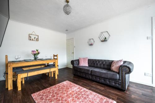 a living room with a black couch and a table at Cosy 3-Bed Home l Free Parking l WiFi l Sleeps 8 l Family Friendly l Hosted by The Cosy Corner Nationwide in Bolton