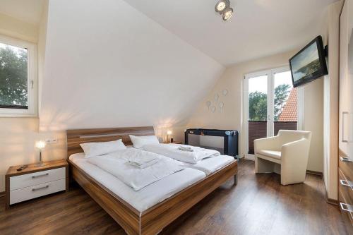 a bedroom with a bed and a tv and a chair at Haus Leuchtturmblick Dünenresidenz-Glowe in Glowe