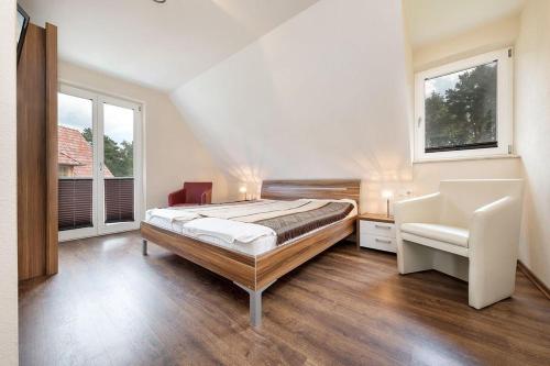 a bedroom with a bed and a chair and a window at Haus Leuchtturmblick Dünenresidenz-Glowe in Glowe