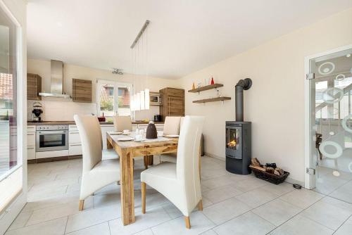 a kitchen with a wooden table and chairs and a fireplace at Haus Leuchtturmblick Dünenresidenz-Glowe in Glowe