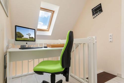 a green chair sitting at a desk with a computer at Haus Leuchtturmblick Dünenresidenz-Glowe in Glowe