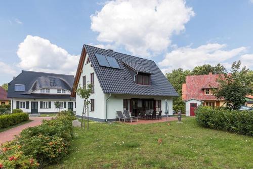 a white house with a black roof at Haus Leuchtturmblick Dünenresidenz-Glowe in Glowe