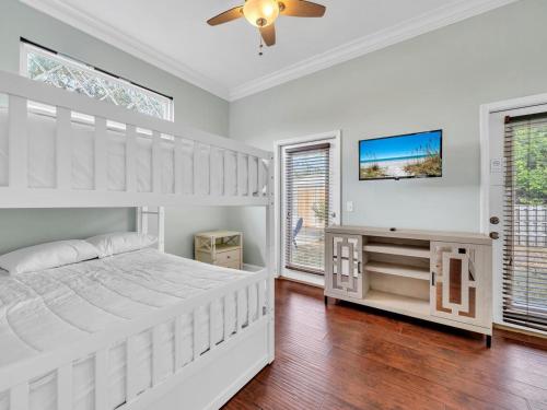 a white bedroom with a bed and a tv at Sandcastle on Castile in Panama City Beach