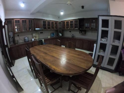 a large kitchen with a wooden table and chairs at Nature Villa Guest House in Matara