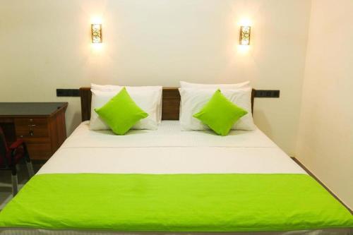 a bed with green sheets and pillows in a room at Nature Villa Guest House in Matara