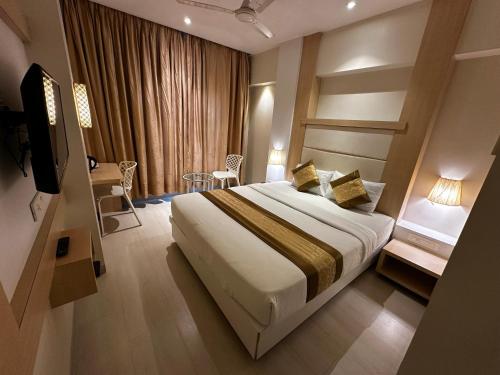 a hotel room with a bed and a television at South Coast Hotel Wagle Estate Thane in Thane