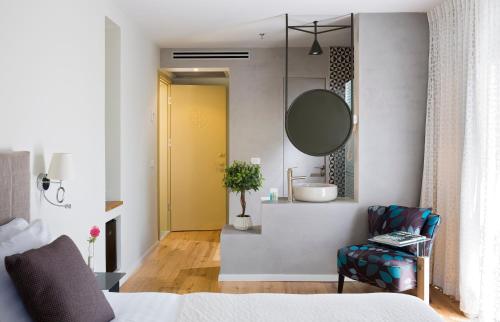 a bedroom with a bathroom with a sink and a mirror at Margosa Boutique Hotel Tel-Aviv Jaffa in Tel Aviv