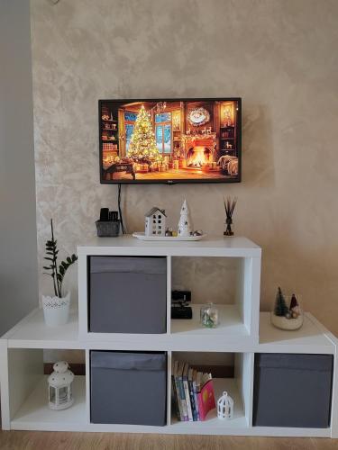 a white shelf with a television on a wall at Apartman Lola in Subotica