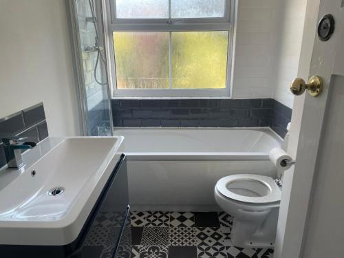 a bathroom with a tub and a toilet and a sink at Whole House - 5 mins to train station, M1 & M69 in Enderby
