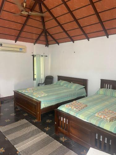 a bedroom with two beds and a ceiling at Yes Yes Farms in Pollāchi