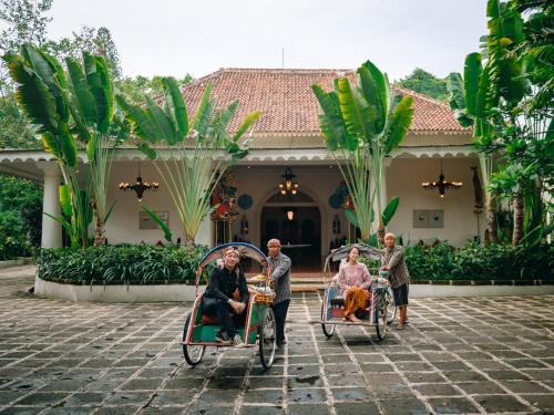 a group of people riding in wheelbarrows in front of a house at Hotel Tugu Blitar in Blitar