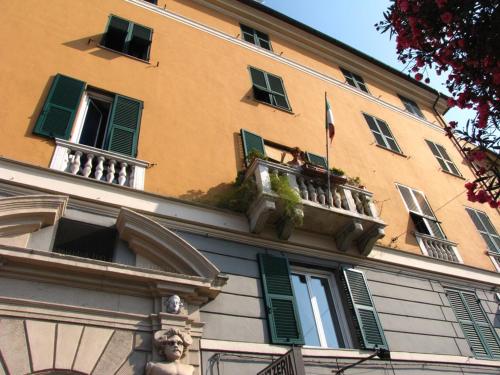 a building with green shutters and a flag on a balcony at B&B Blue Home in Genova