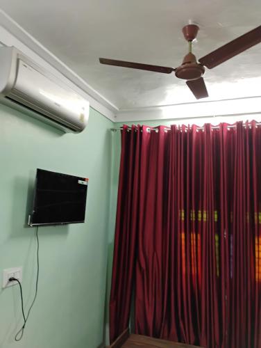 a room with a ceiling fan and a red curtain at Space craft Guest house Heritage villa in kāraikāl