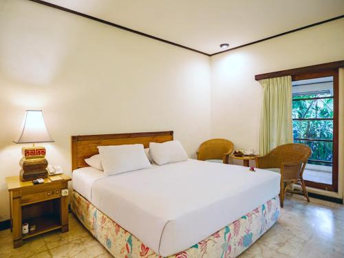 a bedroom with a bed and a table and a window at Hotel Tugu Blitar in Blitar