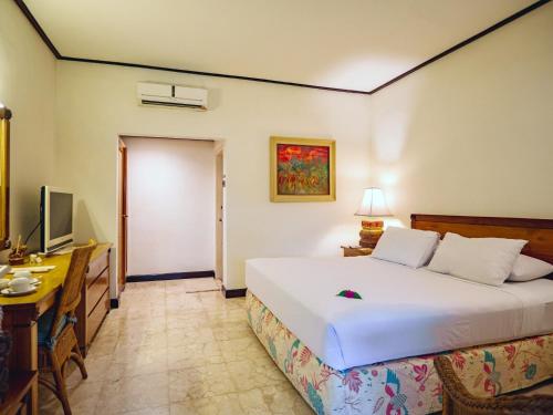 a bedroom with a bed and a desk and a television at Hotel Tugu Blitar in Blitar