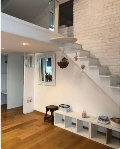 - un salon avec un escalier et un mur blanc dans l'établissement Studio lumineux avec mezzanine, à Lagord