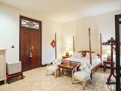 a bedroom with a bed and two chairs at Hotel Tugu Blitar in Blitar