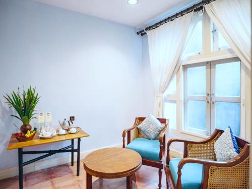a living room with chairs and a table and a window at Hotel Tugu Blitar in Blitar