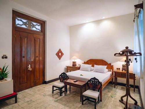 a bedroom with a bed and a table and chairs at Hotel Tugu Blitar in Blitar
