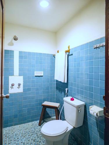 a blue tiled bathroom with a toilet and a stool at Hotel Tugu Blitar in Blitar