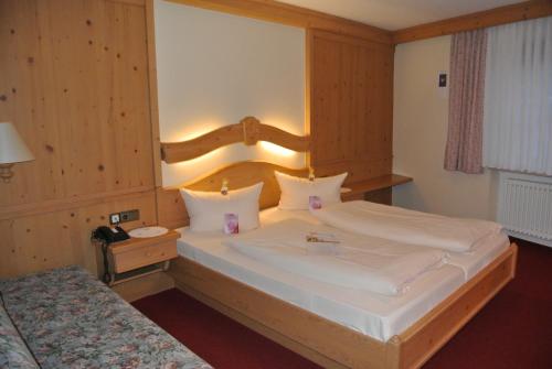 a bedroom with a large white bed with a wooden headboard at AKZENT Hotel Am Bach in Dettelbach