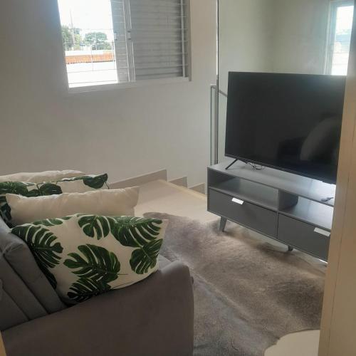 a living room with a couch and a flat screen tv at Suite Versailles in Cuiabá