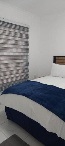 a blue and white bed in a room with a window at Emlomo logde in Ermelo
