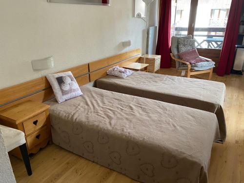 une chambre d'hôtel avec deux lits et une chaise dans l'établissement Studio 4 Pers avec Wifi, Balcon et Parking - Brides-les-Bains - FR-1-512-195, à Brides-les-Bains