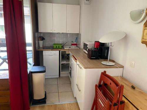 une petite cuisine avec des armoires blanches et une table dans l'établissement Studio 4 Pers avec Wifi, Balcon et Parking - Brides-les-Bains - FR-1-512-195, à Brides-les-Bains