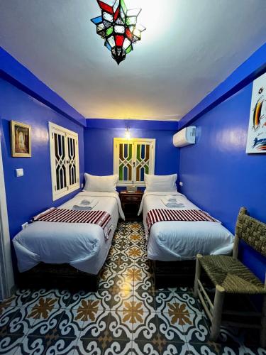 a blue room with two beds and a stained glass window at RIAD CHENGLI 蓝城里 in Chefchaouene
