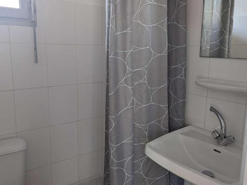 une salle de bain avec un rideau de douche et un lavabo dans l'établissement Appartement ensoleillé avec terrasse et parking, à 2 pas de la plage - Marseillan - FR-1-387-169, à Marseillan