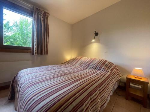 une chambre avec un lit avec une lampe et une fenêtre dans l'établissement Appartement calme à Samoëns avec piscine - FR-1-624-101, à Samoëns