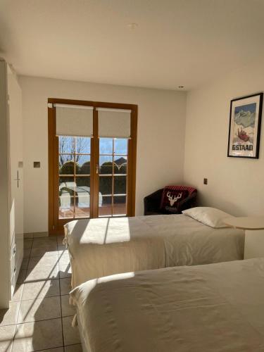 two beds in a room with a window at Le Chalet Rosat Apartment 25 in Chateau-d'Oex