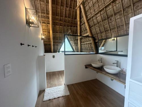 a bathroom with two sinks and a straw roof at Hotel Bambu in Santiago Atitlán