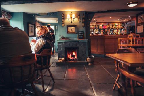 a woman sitting in front of a fireplace in a bar at The White Horse Inn Bunkhouse in Threlkeld