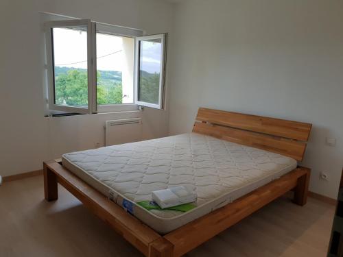 - un lit dans une chambre avec 2 fenêtres dans l'établissement Gîte avec vue, à Hautefage-la-Tour