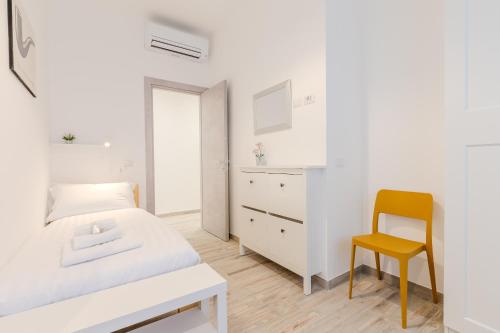 a white bedroom with a bed and a yellow chair at Maria Magdalena Apartment Saint Peter's in Rome