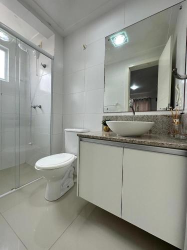 a bathroom with a toilet and a sink and a shower at Apartamento Centro de bombas in Bombinhas