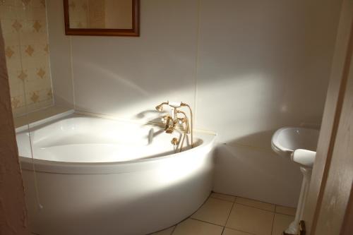a white bathroom with a tub and a sink at Middlegate Hotel in Pembroke
