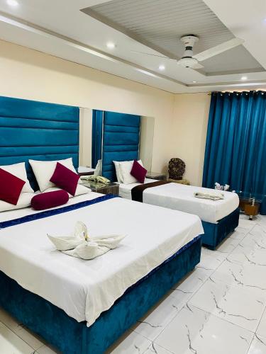 two beds in a hotel room with blue curtains at Hotel Golden in Lahore
