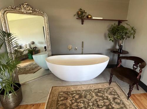 a bathroom with a large white tub and a mirror at Rooiheuwel in Botrivier