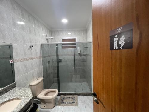 a bathroom with a toilet and a glass shower at Angel Hospedagem Itapuã in Vila Velha